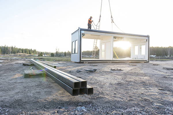 Container med mann på taket heises opp av kran